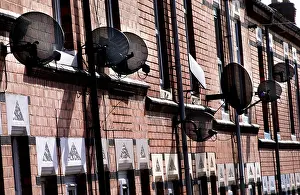 Street House Prints: BSkyB satellite dishes clustered on terraced houses in a side street in Evington Leicester