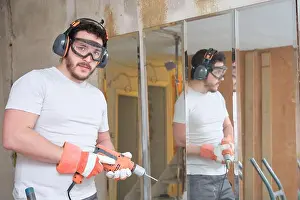 Housework Prints: Builder holding a drill and looking at camera at the construction site