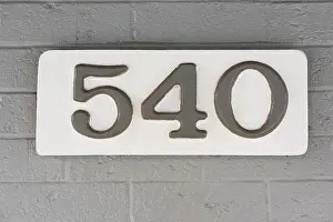 Adornment Prints: Building number five hundred and forty (540) on a white plaque against a grey brick wall