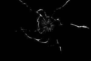Torn Prints: bullet hole in glass close-up on black background