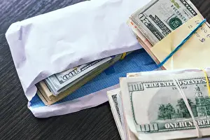 Shady Prints: Bundle of american dollar banknotes in white envelope on wooden table