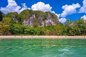 Railay Prints: Bungalow house with red roof among coconut palms near the cliffs with people sunbathing