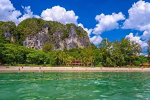 Railay Prints: Bungalow house with red roof among coconut palms near the cliffs with people sunbathing