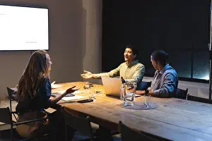 Executives Prints: Business meeting at night, diverse team discussing ideas around conference table
