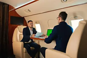 Korean Ethnicity Prints: Two Businessman CEO couple in eyeglasses sitting inside a private jet airplane and talking about work shaking hands