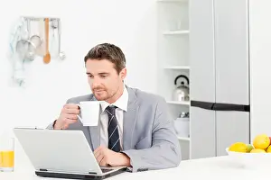 White Work Prints: Businessman drinking while he is looking at his laptop