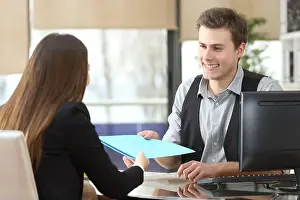 Coworkers Prints: Businessman giving documents to a client sitting at office during an interview