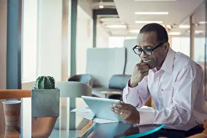 Corporate Business Prints: Businessman working alone in office using digital tablet