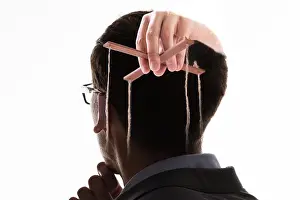 Manipulate Prints: A Businessman's Hand Manipulating Marionette With String Against White Background
