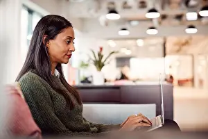 Flexible Prints: Businesswoman Sitting On Sofa Working On Laptop At Desk In Shared Workspace Office