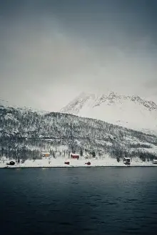 Cabins on the snowy bank by the arctic ocean in the Lyngen Alps in Norway