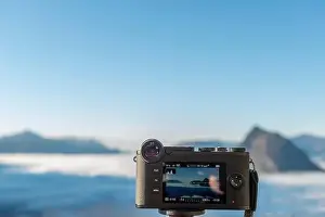Lugano Prints: Camera Filming Mountain Peak San Salvatore Above Cloudscape with Sunlight and Clear Sky in Lugano