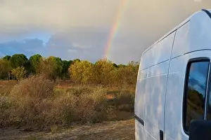 Camper Van Prints: Camper van living vanlife on nature landscape with a rainbow behind it at sunset