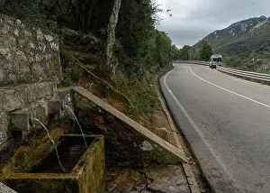 Camper Van Prints: A camper van parked on a mountain highway in the backcountry with a fresh natural spring water fountain