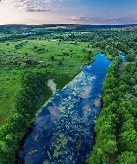 Canoes on the calm river. Top view. Beautiful picture of river and green banks of the river in the summer morning day