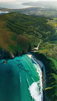 Captivating drone shot capturing a secluded beach surrounded by the rolling green hills of Galicia The coastline