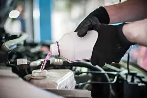 Unclean Prints: Car master mechanic pours antifreeze in the car at service workshop