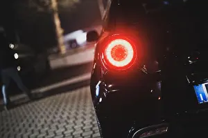 Light Night Prints: Car tail light glowing red on a dark urban street at night