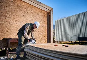 Carpenter Prints: Carpenter using circular saw for cutting wooden OSB board