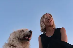 Short Hair Prints: A Caucasian female in a black dress sitting on a rock with a dog at seaside