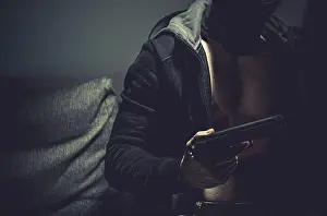 Handgun Prints: Caucasian Gangster Wearing Black Hoodie with Handgun in a Hand Close Up Photo