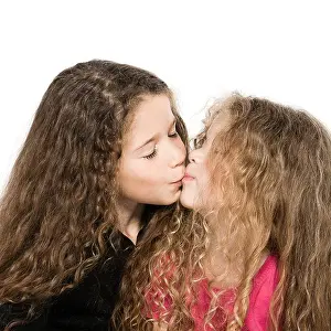 Sisters Prints: two caucasian little girls portrait kissing isolated studio on white background