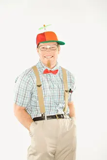 Schoolboy Prints: Caucasian young man dressed like nerd wearing propeller cap with hands in pockets looking at viewer with big smile