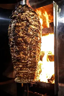 Spit Prints: Charcoal shawarma meat. Closeup of chicken meat collected on a vertical skewer and grilled on charcoal