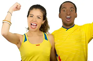 Latino Prints: Charming interracial couple wearing yellow football shirts cheering joyfully to camera