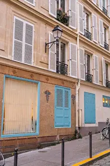 Ironwork Prints: A charming Parisian street corner featuring a building facade with light blue shutters and doors