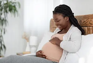 Empty Space Prints: Cheerful African American Pregnant Woman Relaxing On Bed At Home, Touching Belly