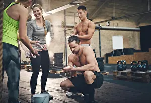 Bodybuilding Prints: Cheerful athletic adults talking while applying talcum powder to hands before doing intense workouts requiring a firm
