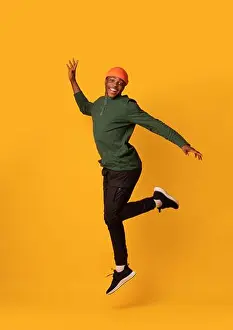 Empty Space Prints: Cheerful Excited Black Hipster Guy Jumping In Air Over Yellow Background