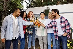 Toasting Prints: A cheerful group of friends rest in nature near a tourist trailer