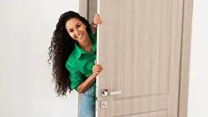 Hiding Prints: Cheerful lady looking out of door standing in doorway
