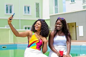 Nigerian Prints: Cheerful young beautiful Nigerian females having fun by the pool and taking selfies