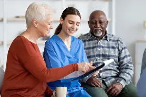 Elderly Prints: Cheerful young woman doctor having conversation with senior patients