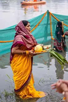 Jharkhand Prints: Chhath Puja, Indian hindu female devotee performing rituals of chhath puja while standing in river to worship lord sun