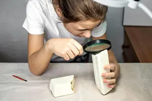 Inspect Prints: Child examines foam block with magnifying glass during a science activity