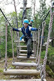 Scout Prints: Child overcoming swinging logs obstacle in forest adventure park, Karelia