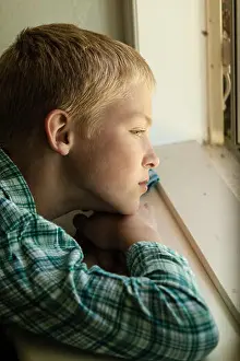 Reflecting Prints: Child with sad expression sitting near window