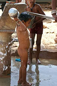 Rajastan Prints: Child washing at village water pump in rural Rajasthan India South Asia