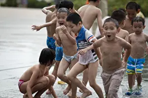 Guangdong Prints: Children play with water to cool themselves off in a hot day at a fountain in Shenzhen city