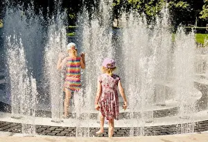 Unrecognizable Prints: Children playing in water splashing fountain in public park
