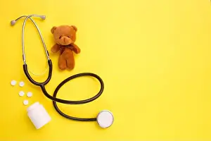 Loop Prints: Children's toy teddy bear with stethoscope on yellow background with copy space