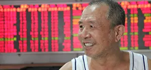 Share Prints: A Chinese investor smiles as he looks at prices of shares (red for price rising and green for price falling)