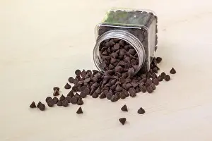 Paste Prints: Chocolates scattered on a wooden table from a plastic jar