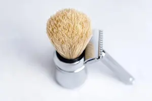 Chrome-plated safety razor and shaving brush isolated on light gray background