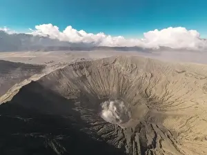 Jeep Prints: Cinematic shot aerial view of Mount Bromo crater with active volcano smoke in East Java