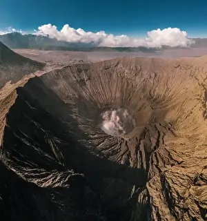 Jeep Prints: Cinematic shot aerial view of Mount Bromo crater with active volcano smoke in East Java